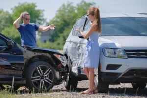 Two people standing by their cars after an accident.