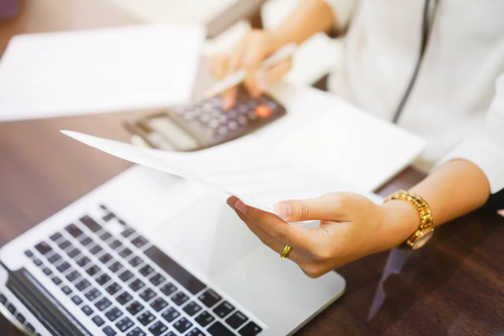 An employee reviewing paperwork and using a calculator to check her wages.
