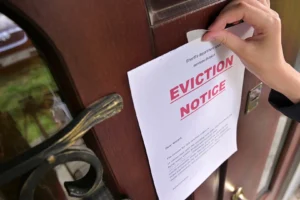 A person hanging an eviction notice on a door.
