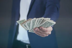 A person wearing a blue suit, handing over a large amount of cash.